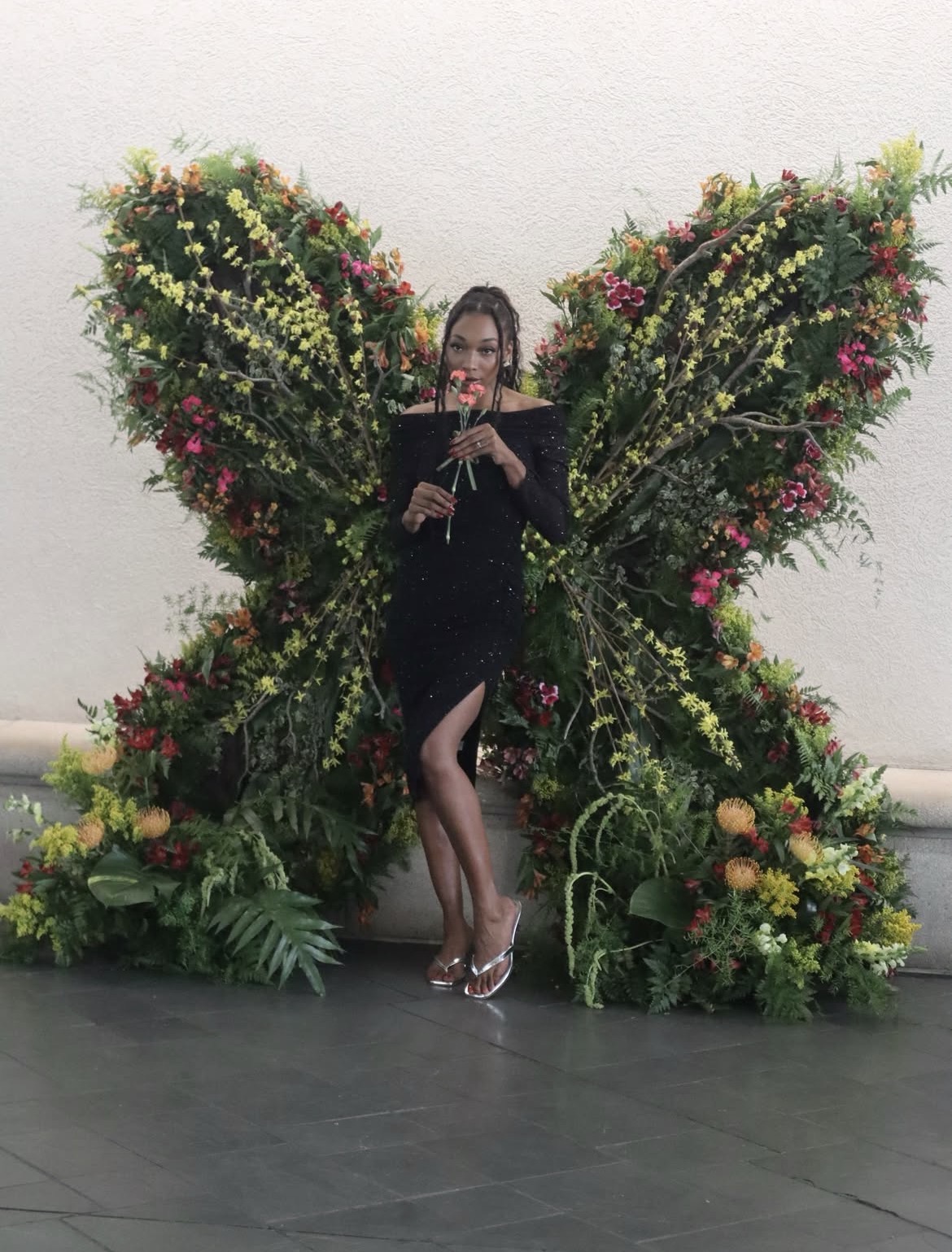 Amari Kelly posing with a floral butterfly installation